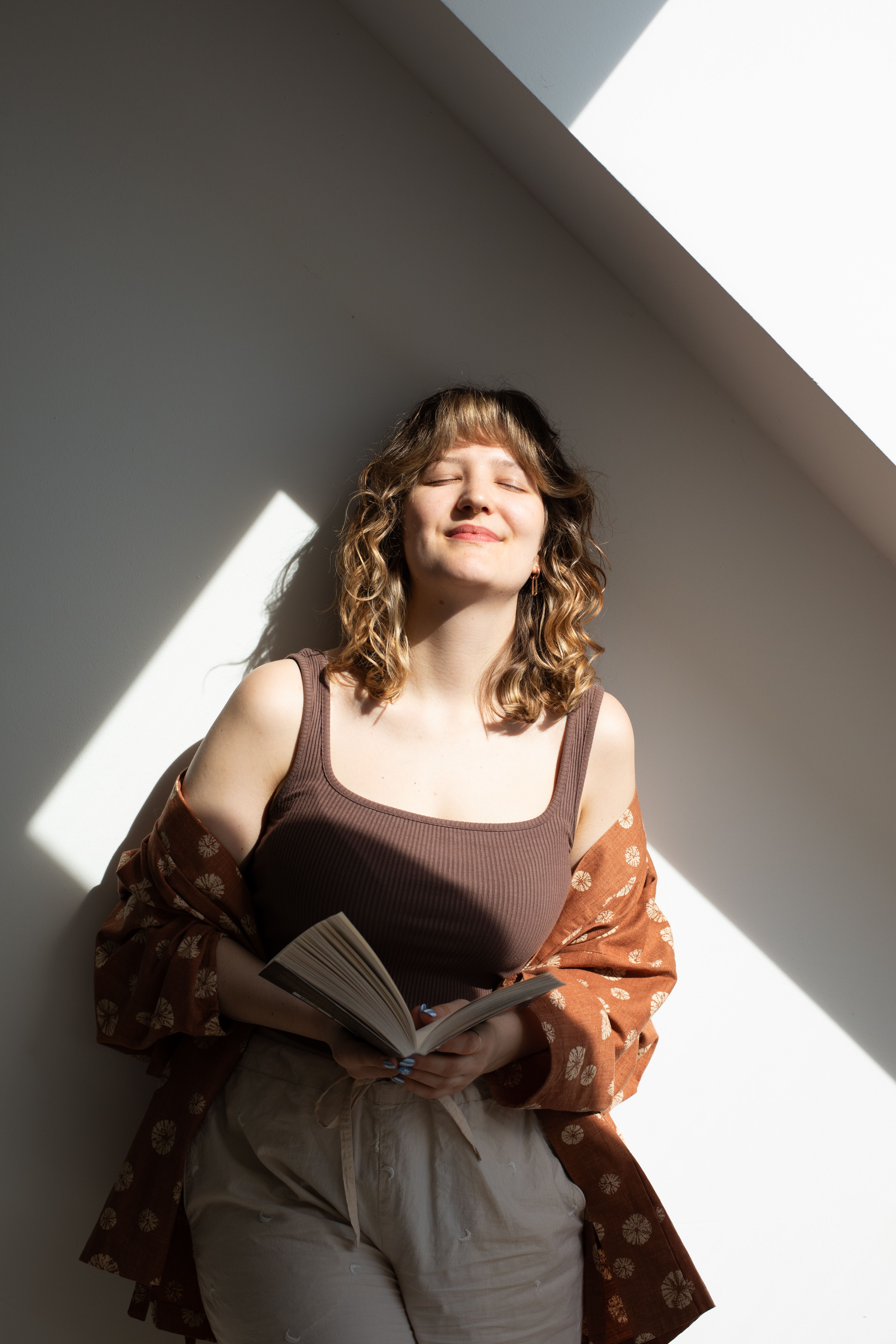 Silke in der Sonne, vor weißer Wand.