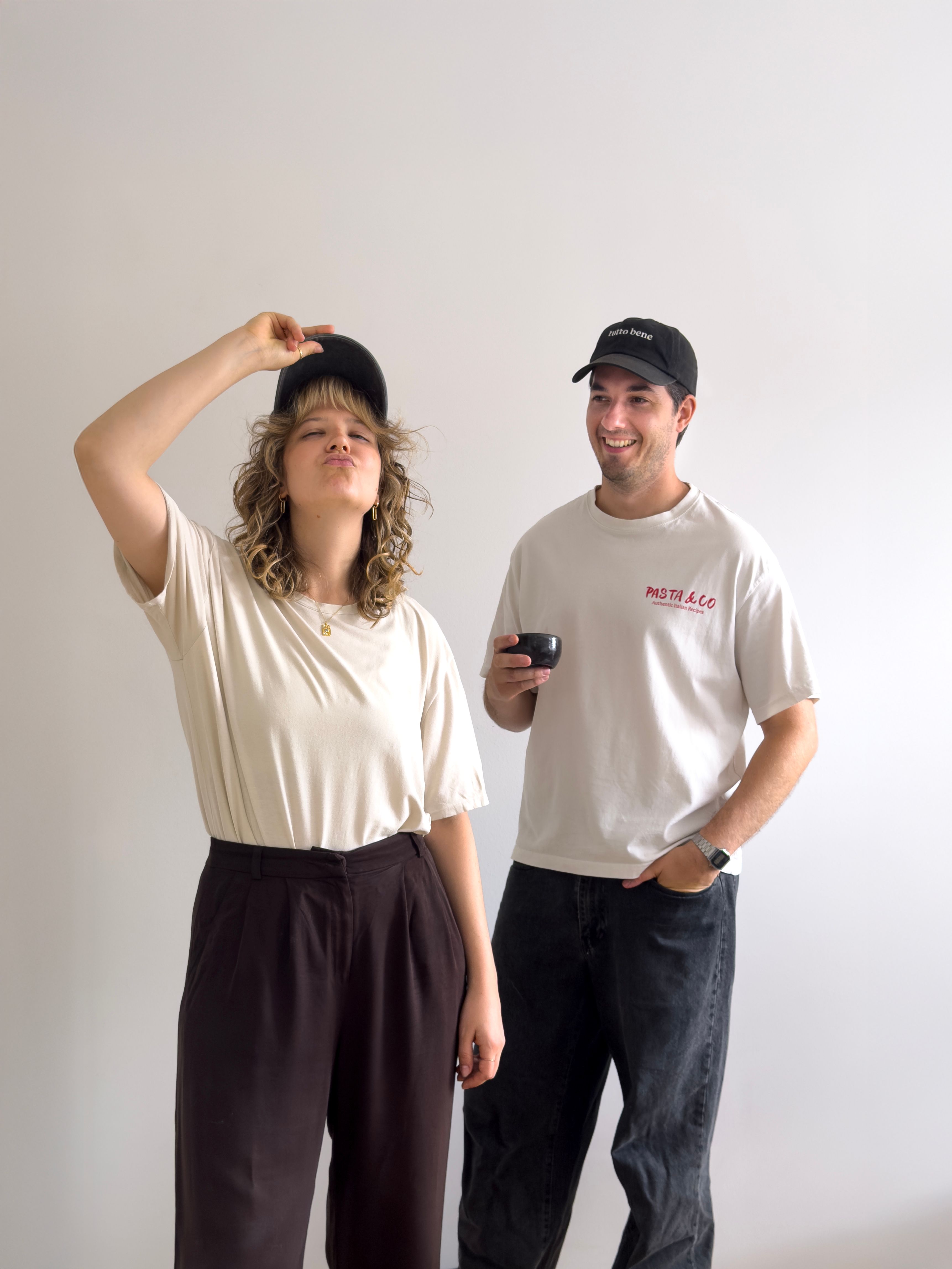 Martin and Silke with a hat in front of a white wall. 