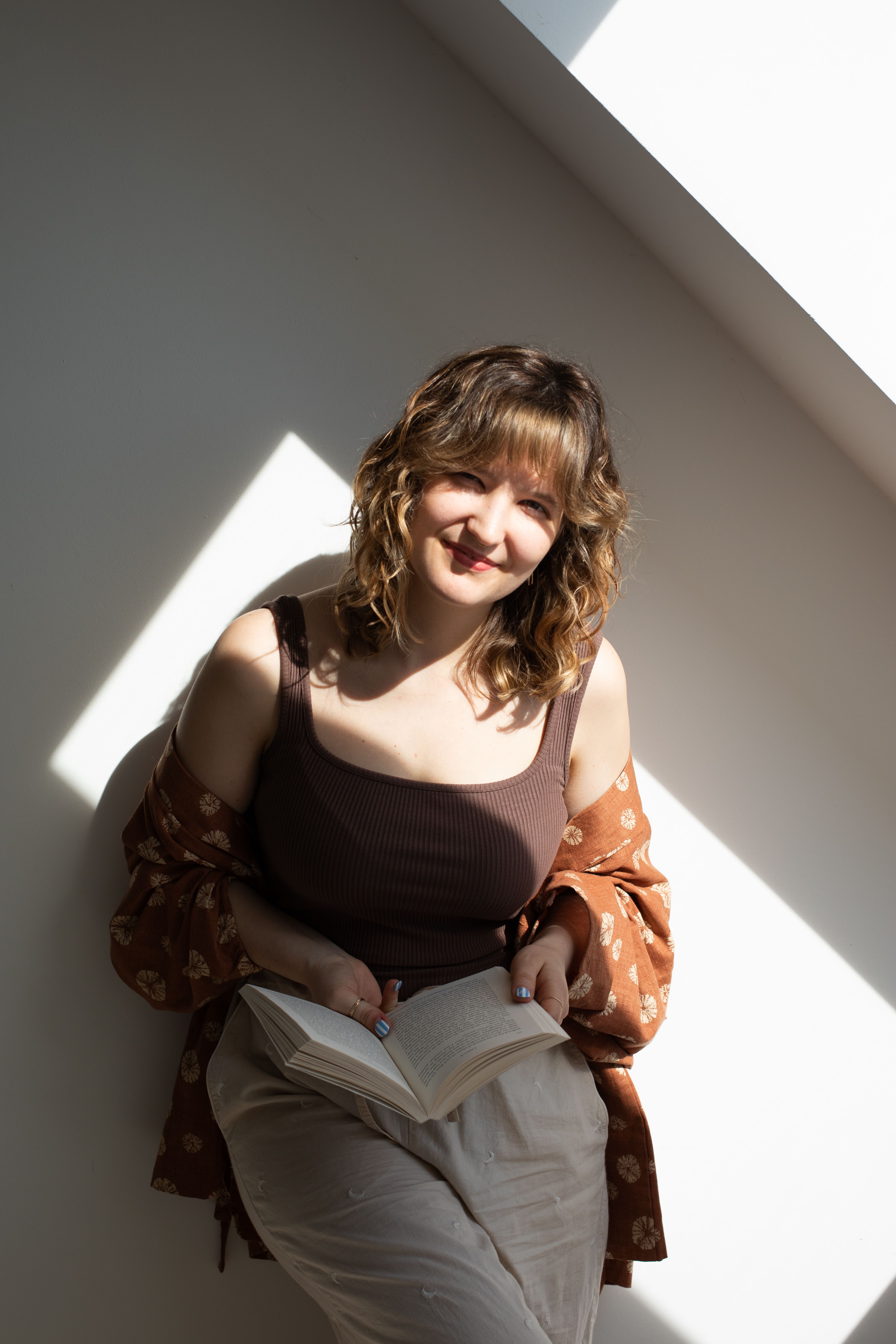 Silke lächelt in die Kamera mit einem Buch in der Hand.